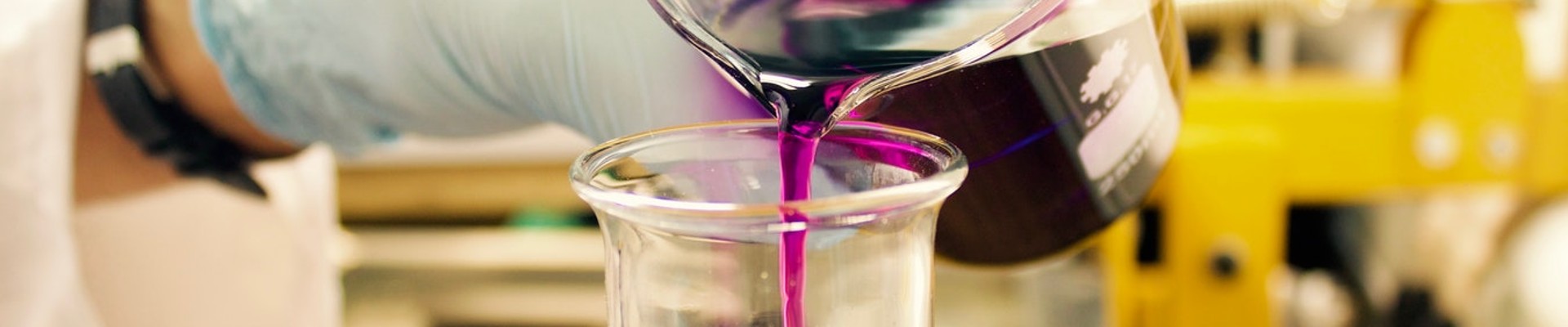 Smiling laboratory chemist wearing glasses and in the background a microscope and test tubes